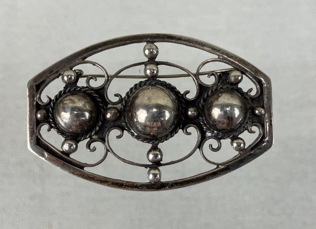 Vintage Sterling Silver Brooch: This sterling silver brooch features an intricate open scrollwork triple dome design paired with an open geometric border. The piece is highlighted by three prominent half-sphere domes accented with t