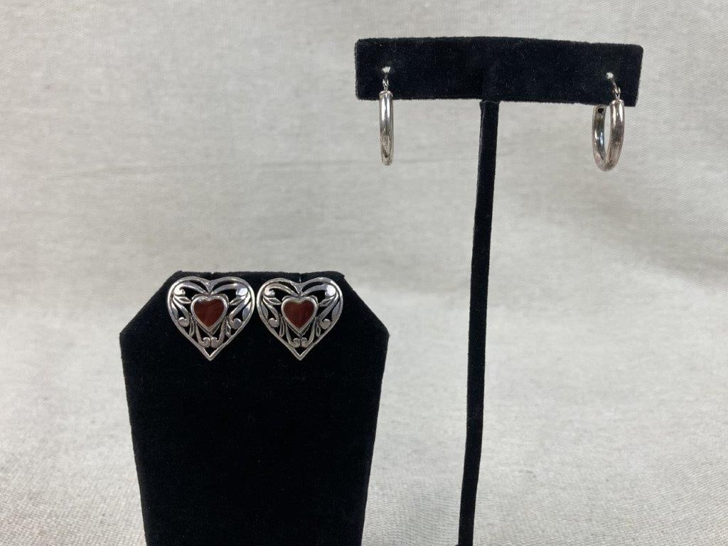 Two Pairs of Sterling Silver Earrings: This sterling silver earring assortment includes one pair of artisan-crafted heart-shaped stud earrings featuring a central warm enamel heart surrounded by a reticulated heart border with intricate