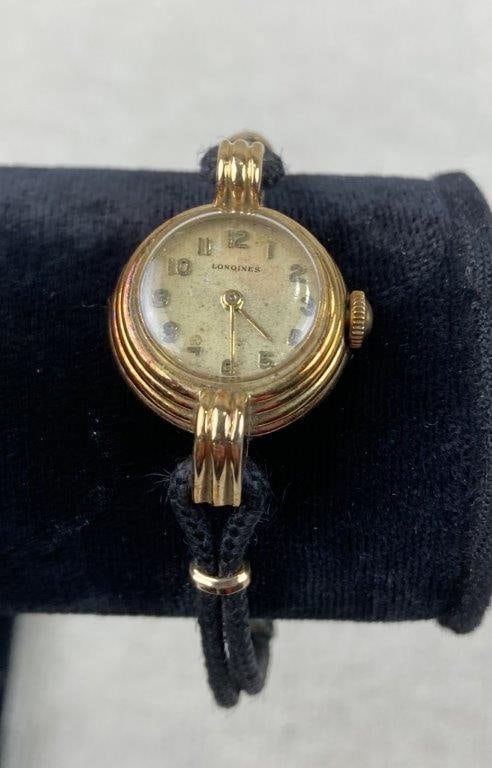 Longines Ladies 14K Gold Cocktail Watch: This Longines ladies cocktail watch features a 14K gold circular stepped case housing a classic champagne dial. The elegant timepiece is styled with a black rope strap finished with 1/20 10K GF