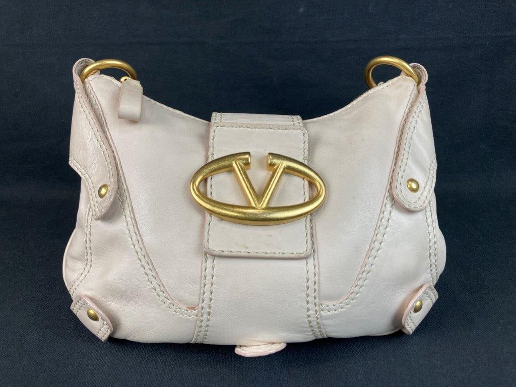 Valentino Garavani V-Ring Leather Shoulder Bag: This Valentino Garavani V-Ring shoulder bag is crafted from off-white cream textured leather and features an inner satin lining with a single zip closure interior pocket. The design is anchored by