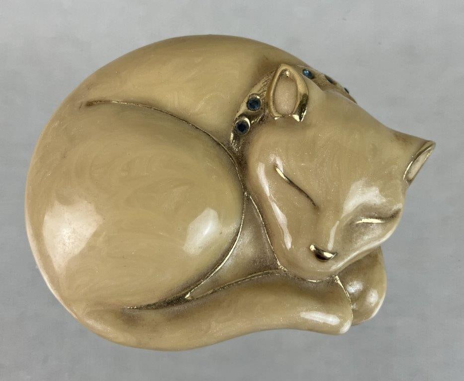 EstÃ©e Lauder Cat Perfume Compact: Vintage enamel perfume compact by EstÃ©e Lauder, modeled as a sleeping cat with a beige pearlescent enamel body, accented by blue rhinestones at the collar and set within a gold tone frame,