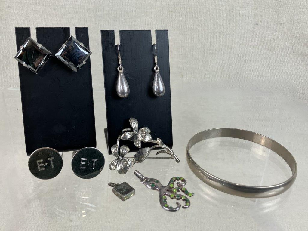 Sterling Silver Jewelry Assortment: This diverse seven-piece sterling silver jewelry collection features an eclectic mix of functional and decorative pieces, including a bangle, monogrammed cufflinks, and a pair of sterling silver and