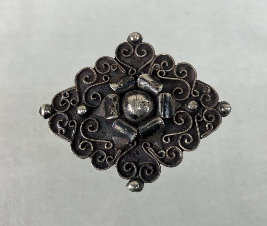 Vintage Mexican Sterling Silver Flower Brooch: This sterling silver brooch features a scrolled wire field with a simple flower in the center. The piece is stamped "Made in Mexico" along with a maker's mark. It weighs 15.64 grams and measures