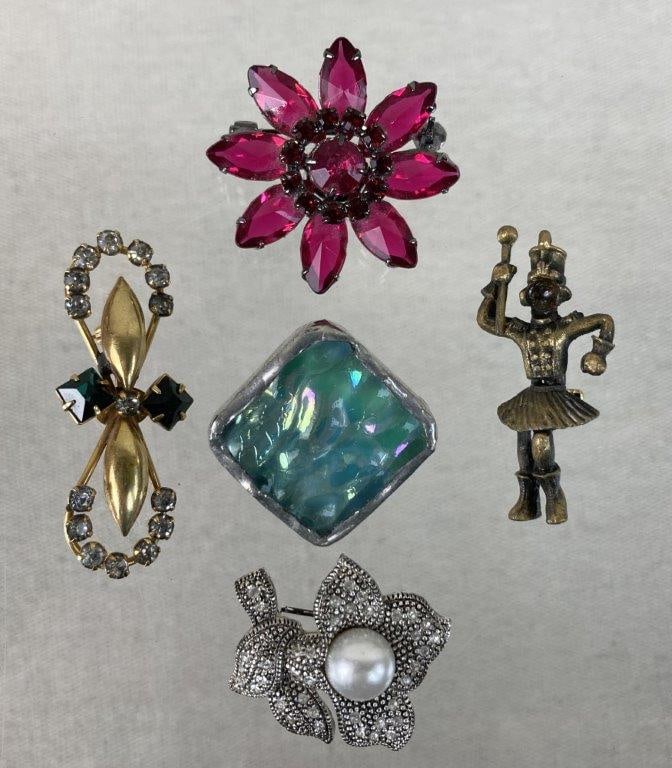 Vintage Brooch Assortment: This five-piece assortment of brooches features a variety of classic styles, highlighted by a standout vintage gold-tone brooch showcasing central emerald-toned rhinestones with a circular rhinestone