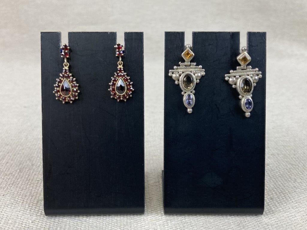 Two Pairs of Sterling Silver Earrings: This two-pair collection of sterling silver earrings features distinct geometric and gemstone designs. The lot includes a pair of teardrop-shaped earrings beautifully set with garnet stones