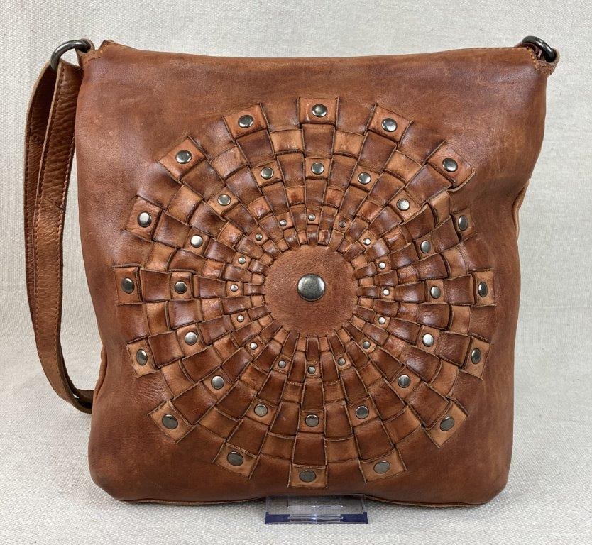 Vilenca Holland Woven Leather Bag: A tactile and artisan-inspired crossbody bag from Vilenca Holland, expertly crafted from rich brown pebbled leather. The focal point of the design is a prominent circular medallion on the front,