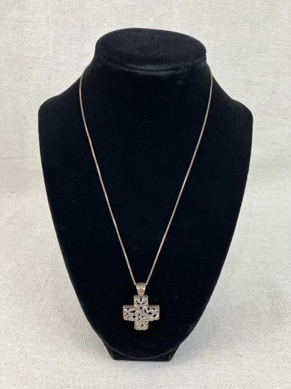 Sterling Silver Openwork Cross Necklace: Sterling silver necklace featuring a cross pendant defined by decorative scrollwork with a reticulated openwork design, suspended from a delicate silver chain. Chain measures approx. 16" in length;