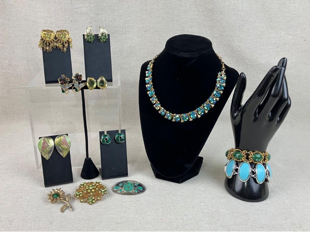 Gold Tone Costume Jewelry Assortment: Group of twelve pieces of vintage costume jewelry in cool tones of green and blue, set in gold tone, including examples with enamel, faux stones, and rhinestones, featuring a standout rhinestone