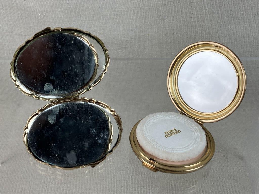 Two Gold Tone Makeup Compacts Including Merle Norman: Pair of vintage gold tone makeup compacts, including one by Merle Norman retaining interior powder with a striped exterior, and one marked Made in Japan featuring an interior mirror and filigree