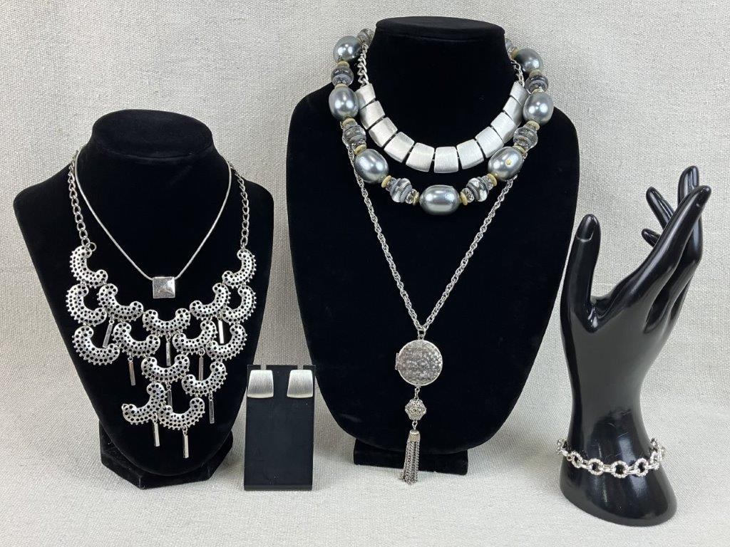 Assortment of Silver-tone Jewelry: A seven-piece silver-tone collection featuring a variety of textured and ornate designs. The set is highlighted by a round locket necklace featuring a dangling ornate metal tassel on a 24 in chain,