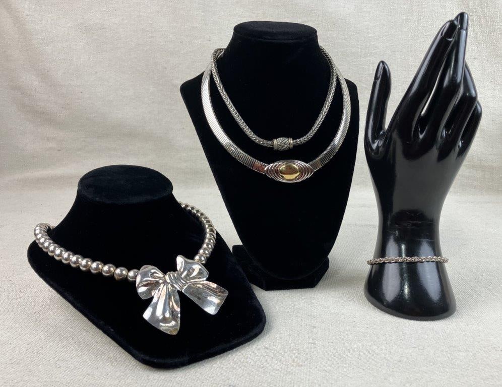 Assortment of Silver-tone Necklaces and Bracelet: This collection features a silver-tone omega chain choker by KJL for Avon with a central gold-tone circle, alongside a silver-tone beaded necklace accented by a bow pendant. The set is completed by a