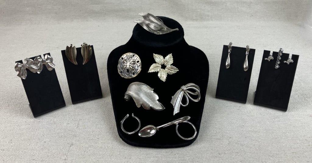 Assortment of Silver-tone Jewelry: This collection features a curated selection of silver-tone accessories, including four pairs of earrings with notable designs in the style of bows and leaves; some in sterling silver. The set is