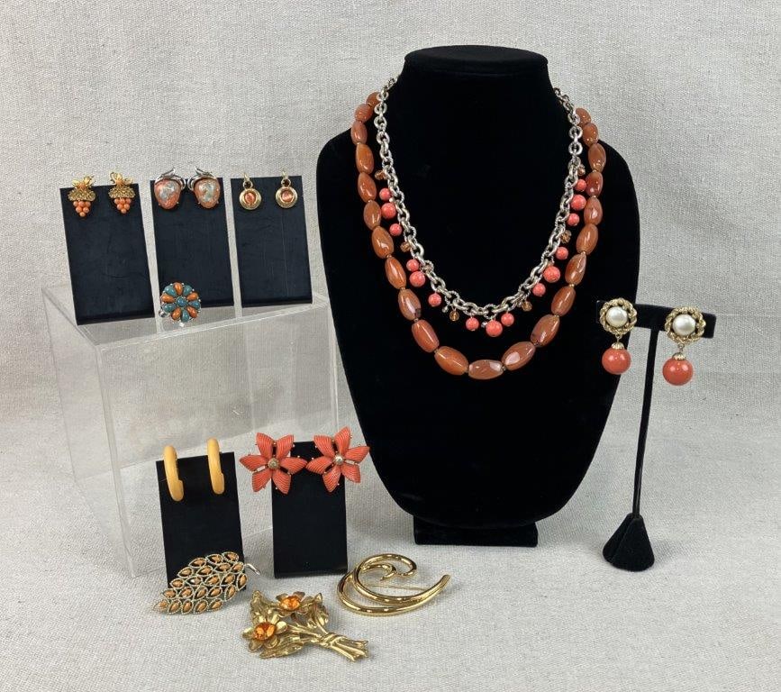 Assortment of Coral Toned Jewelry Including Trifari and Coro: Group of twelve pieces of vintage costume jewelry in coral tones and gold tone settings, including a Trifari brooch with a bold swirling design, a pair of Coro earrings with central faux pearls and da