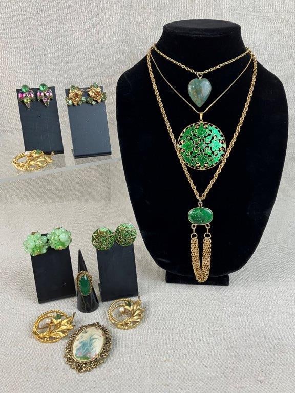 Vintage Costume Jewelry Assortment in Green Tones: Group of twelve pieces of vintage costume jewelry featuring green stones and faux elements throughout, including a brooch with a hand-painted bird and floral motif signed by the artist and dated
