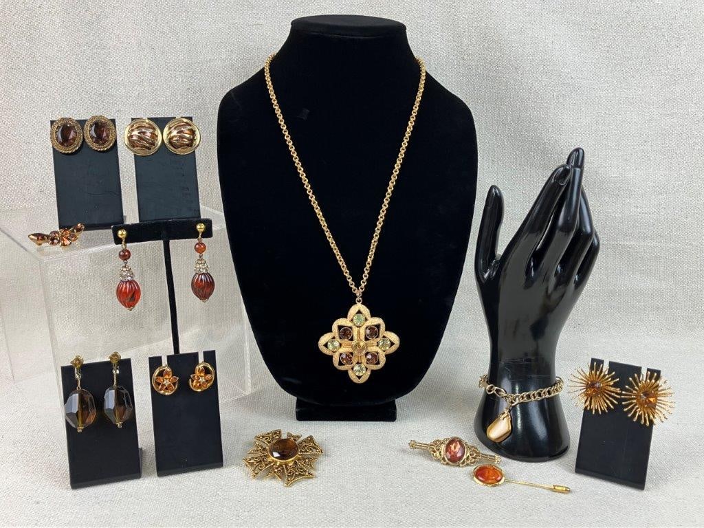 Assortment of Amber and Gold-toned Jewelry Including Sarah Coventry: This twelve-piece collection of vintage gold-tone costume jewelry features a warm, autumnal palette of amber hues and iconic designs. A highlight of the set is a unique stick pin featuring a portrait 