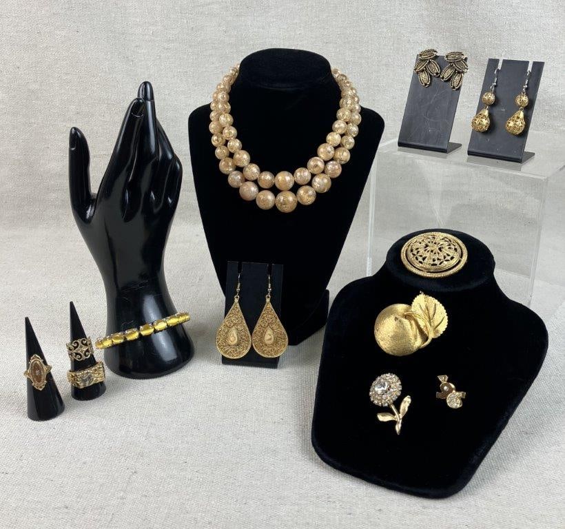 Collection of Gold-Tone Jewelry: This eclectic jewelry collection features a blend of natural textures and bold metallic finishes. The set is headlined by a calcite bead necklace, offering a soft, organic contrast to the gold-tone