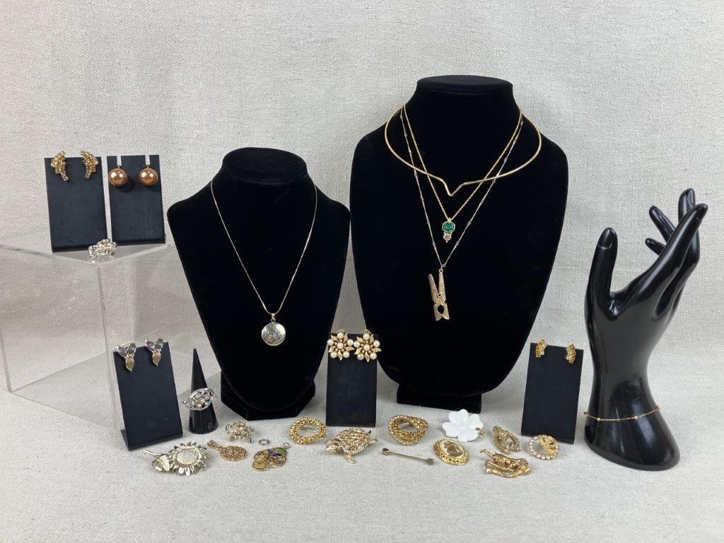 Gold-Tone Costume Jewelry Assortment: This twenty-one-piece collection of gold-tone costume jewelry showcases a whimsical variety of motifs, including an enamel dogwood-style brooch, an ornately framed pendant, and a figural depiction of