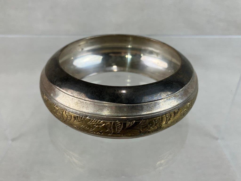 Vintage Sterling Silver and Mixed Metal Bangle Bracelet: This wide band bangle bracelet is crafted from sterling silver and features an encircling brass-tone band decorated with a detailed incised foliage motif. While unmarked, the metal has been tested as