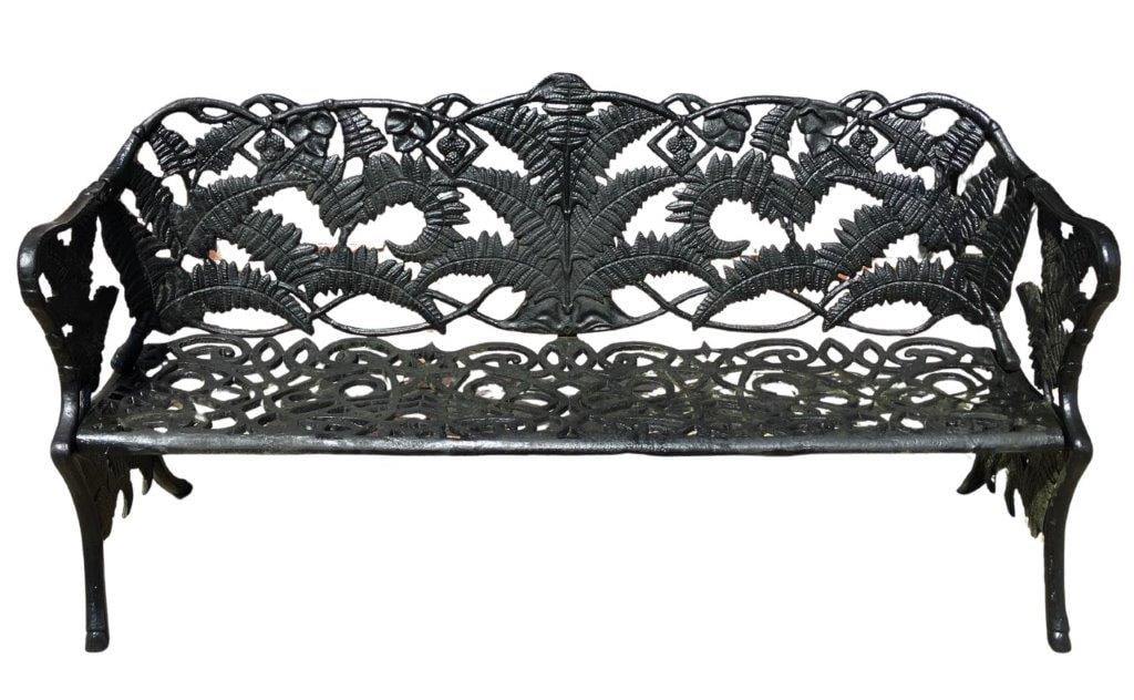 Cast Iron Fern Motif Garden Bench: An early 20th century cast iron garden bench after the iconic Coalbrookdale "Fern and Berry" pattern, executed in black painted iron. The bench features an ornate relief fern decorated back, a