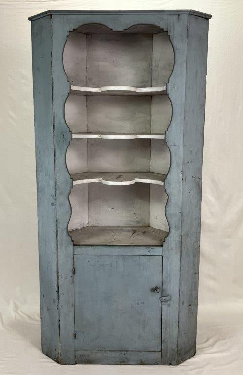 American Painted Corner Cupboard: An exceptional example of 19th century American vernacular furniture, this painted corner cupboard exhibits a classic canted triangular form. The piece is surmounted by a molded cornice above an open