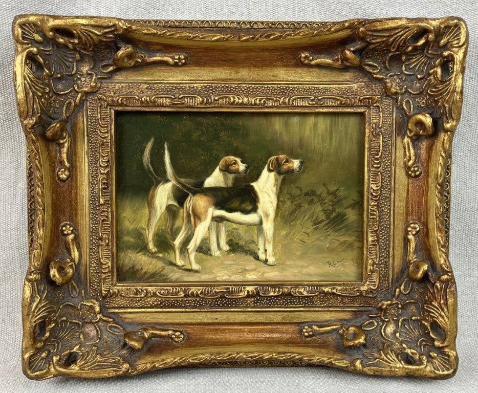 Fox Hounds, Oil on Board: An early 20th century oil on board depicting two sporting foxhounds standing at attention in a field. The work is artist signed lower right and is presented in an ornate gold frame. The frame