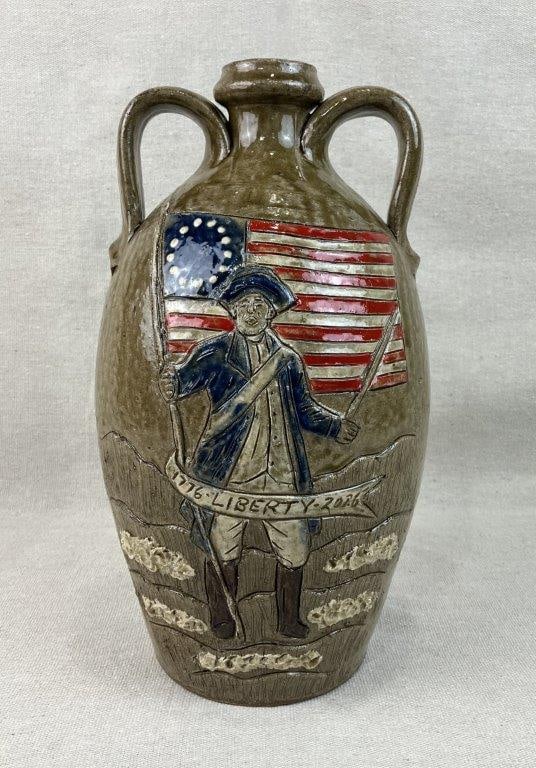 Clint Alderman Patriotic American Jug: An exceptional commemorative folk art jug by acclaimed regional potter Clint Alderman depicts a striking Revolutionary War soldier with a sword alongside an American flag and incised text reading