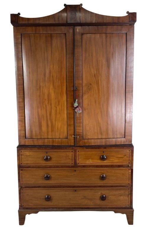 19th Century English Mahogany Linen Press: A handsome 19th century English linen press with a scrolled pediment, paneled doors opening to multiple drawers on one side and hanging space for clothes on the other, above two over two drawers. The 