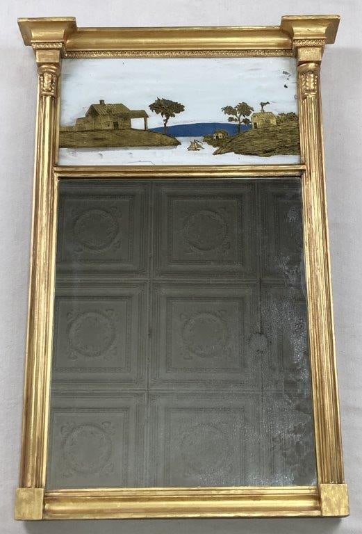 Federal Eglomisé Mirror: A fine Federal eglomisé mirror featuring a reverse-painted seascape on the top panel, flanked by two stately gilt and reeded columns on either side of the mirror plate. The piece displays