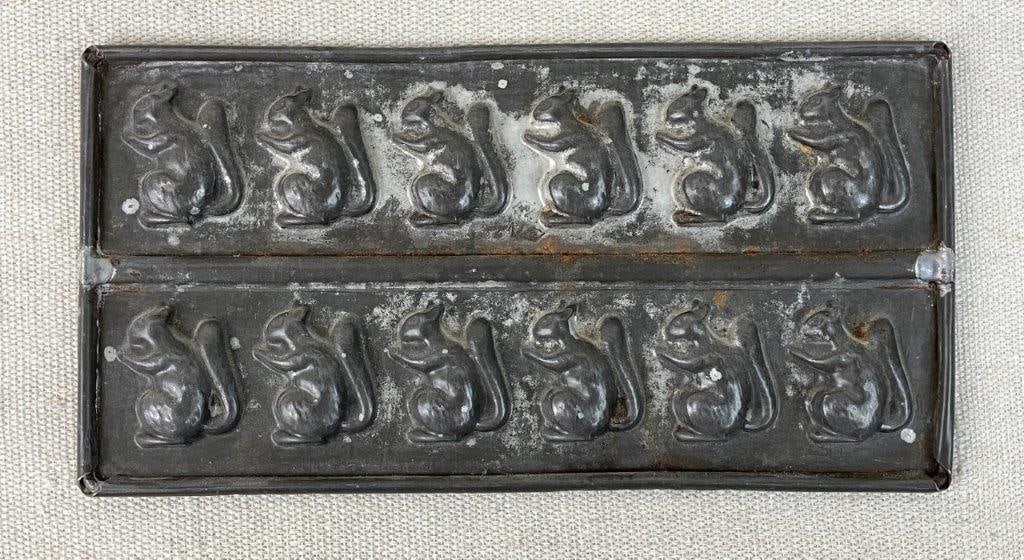 Squirrel Candy Mold: This charming confectionery mold features multiple small squirrel impressions arranged across a single metal pan. Ideal for holiday treat-making or as an eye-catching display piece for a rustic or