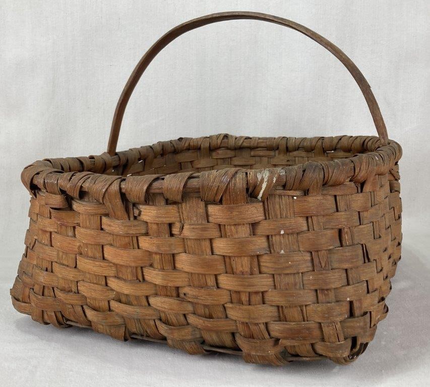 Country Gathering Basket: This traditional hand-woven country gathering basket is constructed from split oak. The piece features a substantial rectangular form, an integrated sturdy carrying handle, and a wrapped, reinforced r