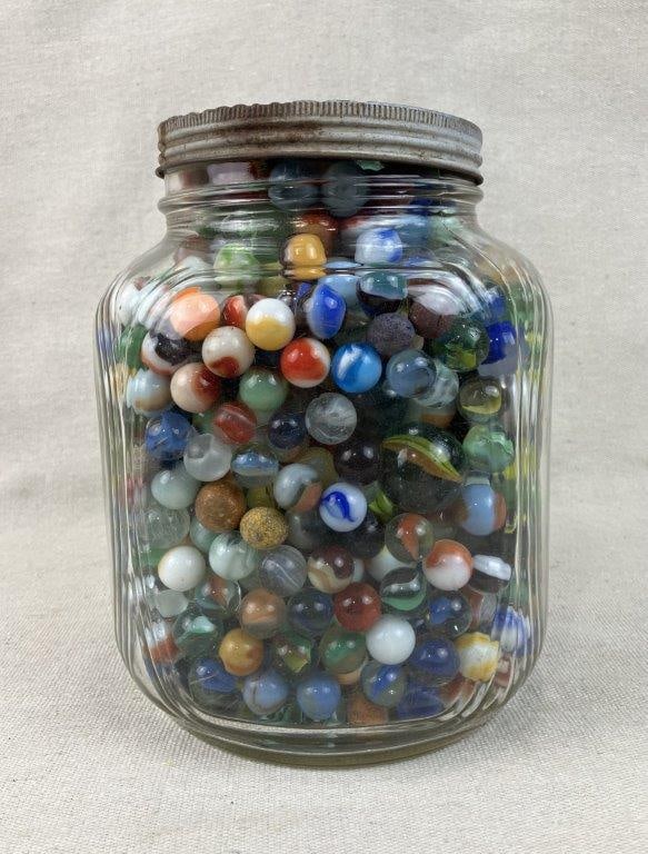 Large Duraglas Ribbed Glass Jar of Marbles: A large Duraglas ribbed glass canister filled to the brim with a substantial collection of antique and vintage marbles. The clear glass jar features classic horizontal ribbing and displays a strong