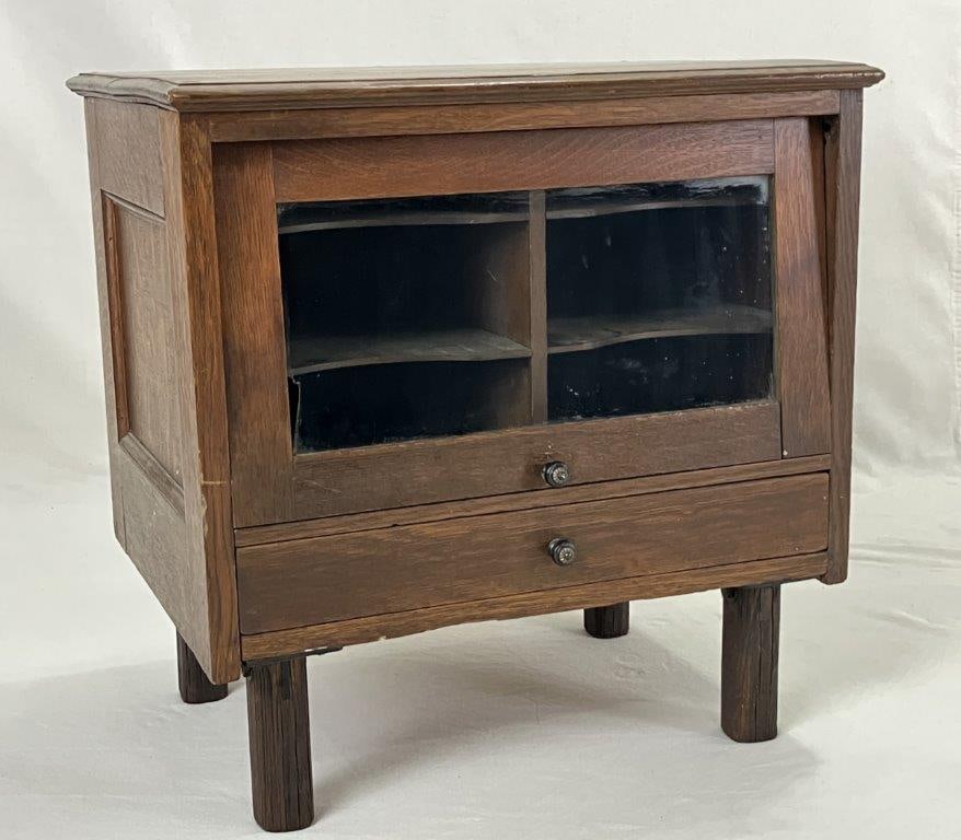 20th Century Oak Music Stand: A 20th century oak music stand with a fine warm finish, featuring a glass door that slides up and a drawer below. It measures approximately 22 inches high x 22 inches wide x 16 inches deep. Some loss 