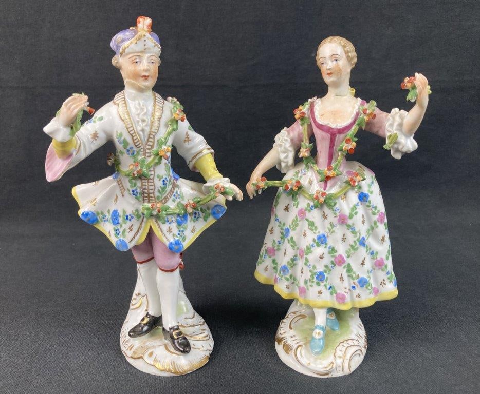 Carl Thieme Dresden Porcelain Figures: This pair of Carl Thieme Dresden porcelain figures depicts a male and female figure beautifully rendered in a pastoral Rococo style. Each piece features vibrant hand-painted details, soft blue eyes,