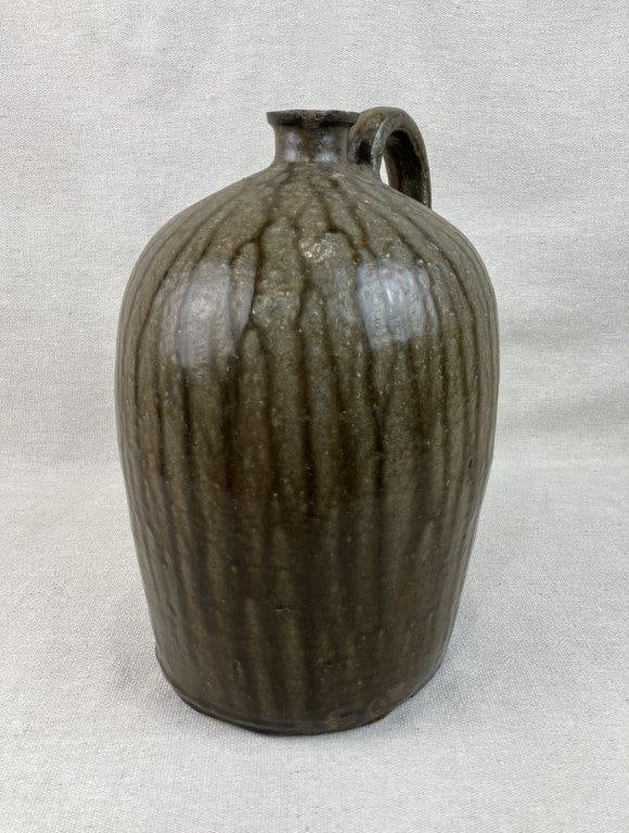 Southern Alkaline Glaze Stoneware Jug: This striking Southern stoneware jug features a rich, runny alkaline glaze that creates a beautiful, dynamic surface texture characteristic of traditional regional folk pottery. The vessel showcases a