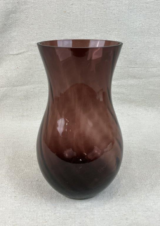 Amethyst Art Glass Vase: This striking amethyst art glass vase features a mesmerizing swirling pattern that ripples gracefully across its gently curving, elegant form. The rich purple hue catches the light beautifully,