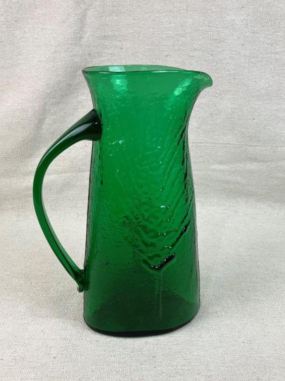 Mid-Century Modern Emerald Art Glass Pitcher: This striking mid-century modern art glass pitcher features a richly colored, blown emerald green body defined by an eye-catching angular relief design. The elegant vintage form is complemented by a