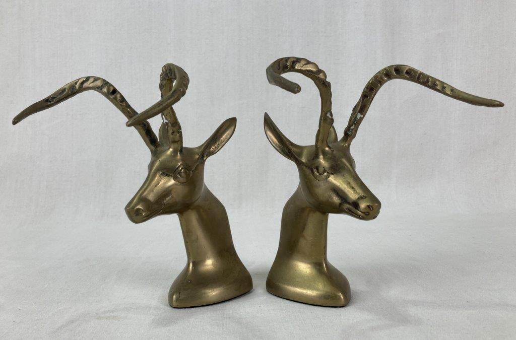 Mid-Century Modern Brass Gazelle Bookends: A pair of mid-century modern cast brass bookends in the form of gazelle busts, featuring detailed horns, expressive faces, and long ears. The pair displays a worn patina. One measures approximately 8