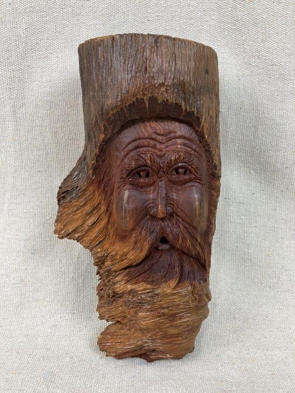 Folk Art Wood Tree Spirit Carving: Captivating wood carving showcases exceptional folk artistry, expertly defining a whimsical face emerging right from the natural contours of a tree stump. The intricately sculpted facial features