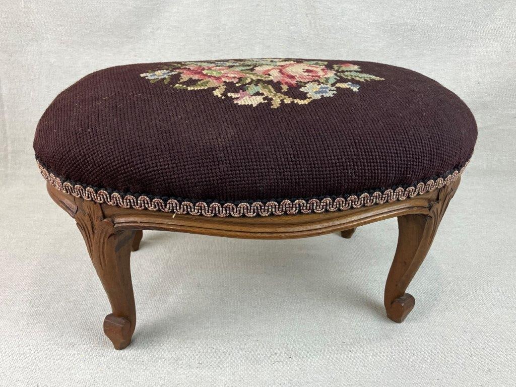 French Needlepoint Footstool: A French needlepoint footstool with finely carved accents and a central bouquet of roses. It measures approximately 8 inches high x 15 inches wide x 9Â½ inches deep. In good condition.