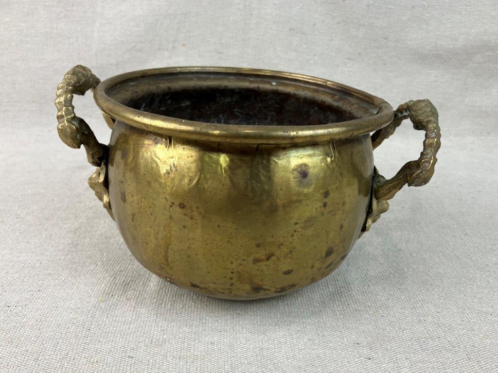 Hammered Brass Pot with Lion Handles: This charming small French-style hammered brass pot features two distinctively detailed, sculptural lion head handles flanking its sides. The vessel boasts a classic hand-hammered texture that