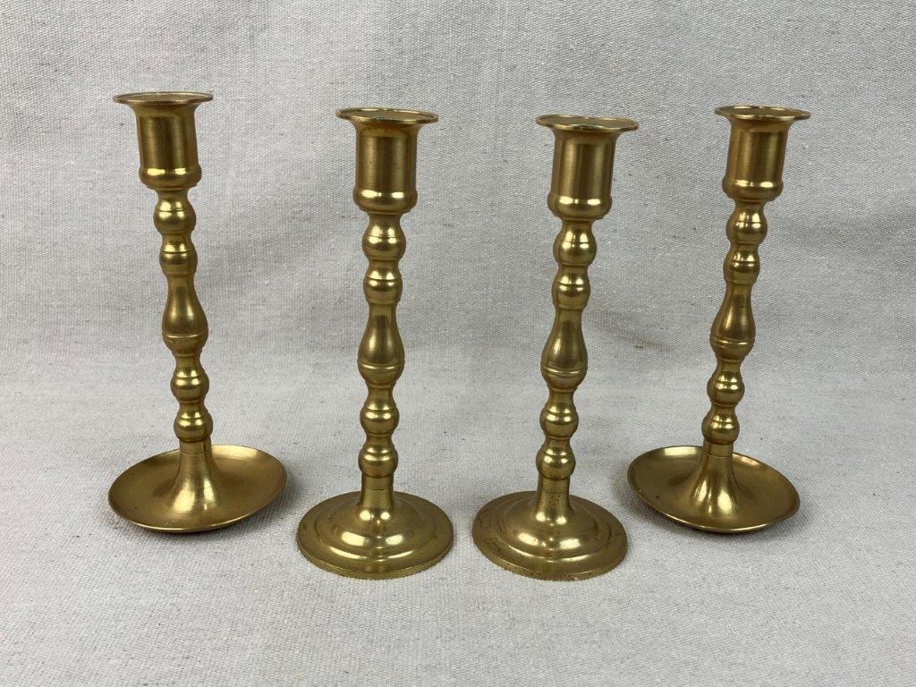 Four Brass Candlesticks: Handsome set of four brass candlesticks features a traditional design defined by elegant, curving profiles that bring a timeless sophistication to any tabletop or mantel display. One candlestick