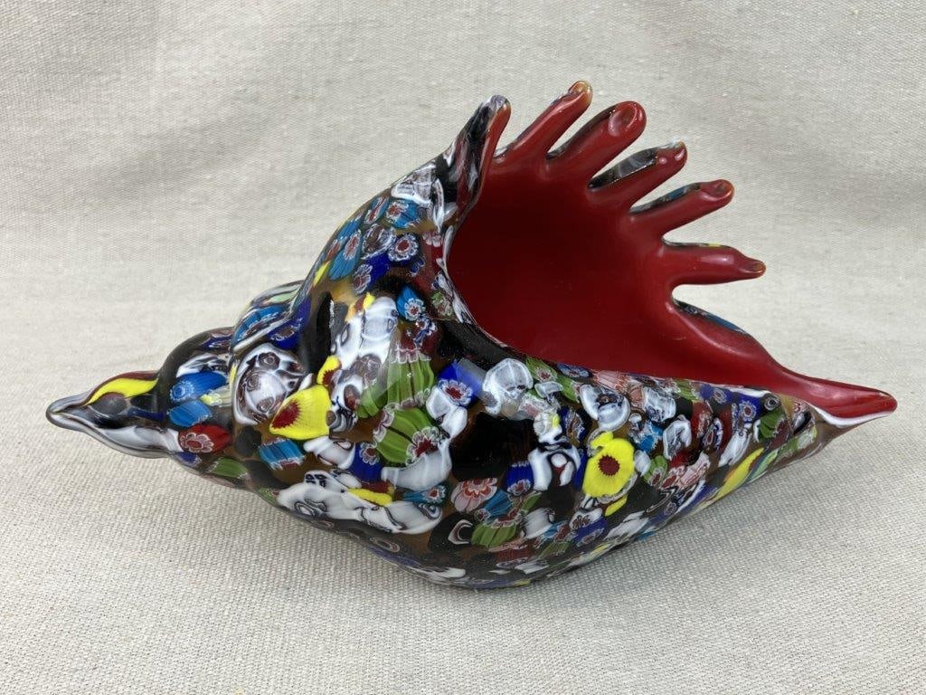 Art Glass Conch Shell: Striking art glass sculpture is beautifully fashioned in the form of a conch shell, showcasing a vividly colored glass body adorned with intricate, Italian-inspired millefiori painted cane designs.