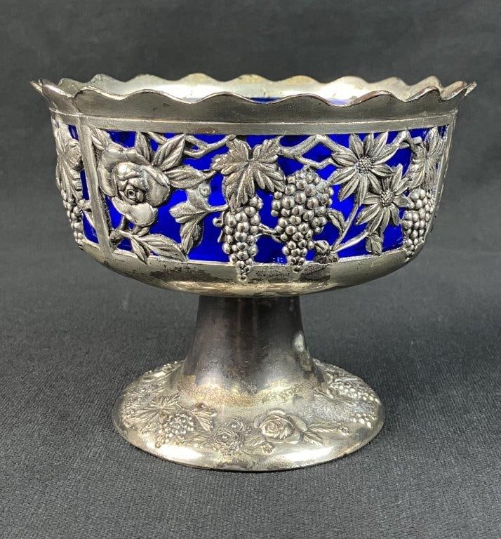 Silver Plate Cobalt Glass Pedestal Bowl: This elegant pedestal bowl features an open-work silver-plate frame decorated with intricate pierced motifs of grapes, vines, and flowers, supported by a base with coordinating embossed motifs. The