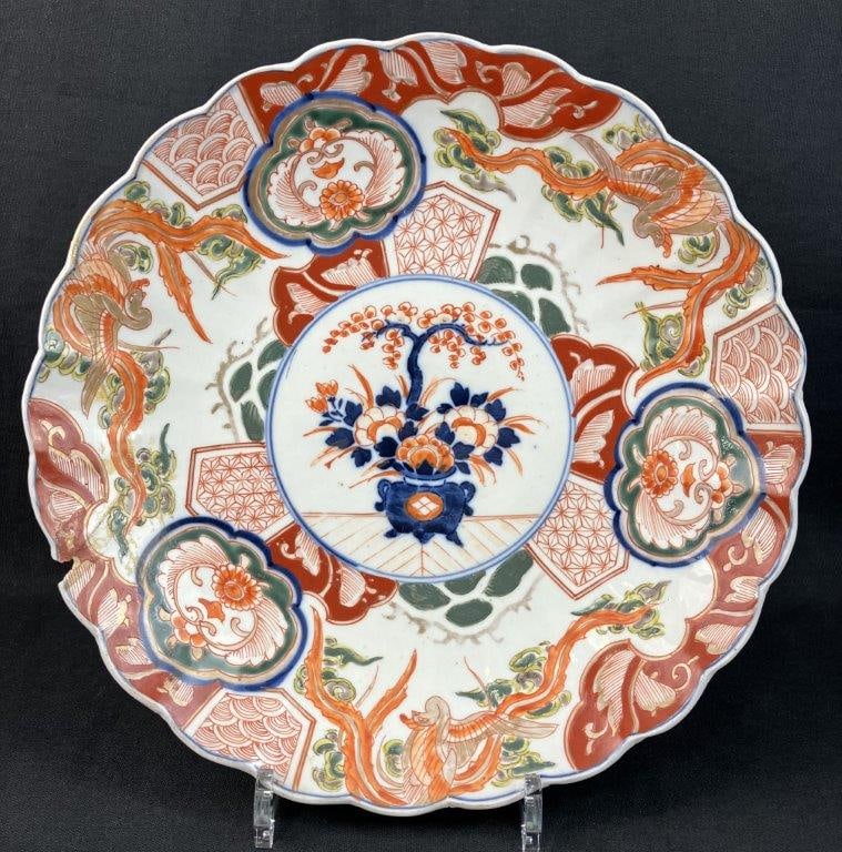 Japanese Imari Porcelain Plate: Elegant Japanese Imari charger plate is crafted in the traditional form, featuring a rich decorative layout of stylized phoenix motifs, lush plant life, and intricate geometric patterns. The piece