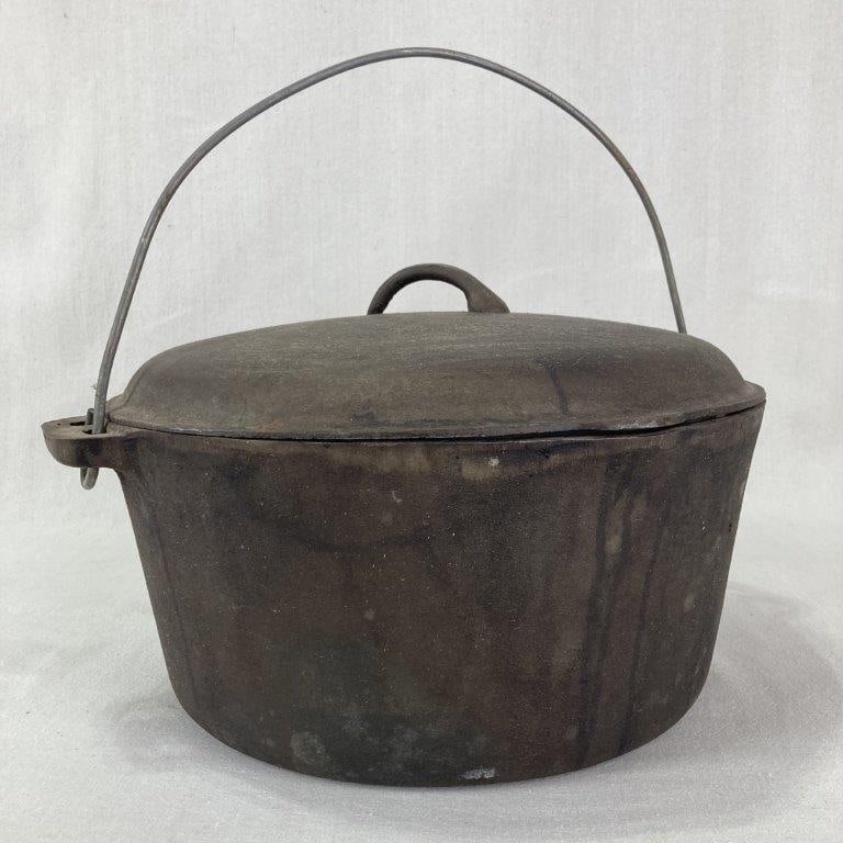 Large Cast Iron Covered Pot: A large cast iron covered pot with a bail handle and fitted lid with a small knob handle. The number "12" is clearly stamped on the top of the lid under the handle and on the base of the pot. The piec