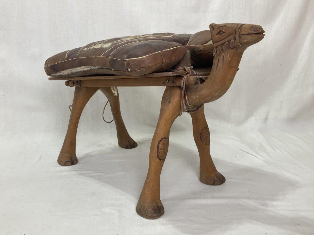 Moroccan Camel Saddle Footstool: A figural Moroccan camel saddle footstool with a tooled leather seat. The piece displays traditional North African craftsmanship with good form and character. It measures approximately 19 inches high