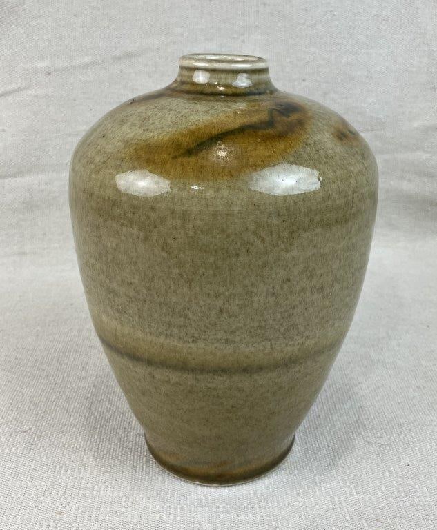 Studio Pottery Vase: This elegant studio pottery vase features a natural speckled glaze rendered in rich, warm earth tones. The vessel showcases an expertly crafted, curving form distinguished by a narrow base and lip tha
