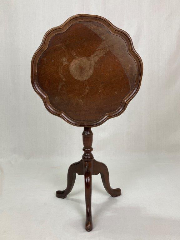Tilt Top Stand: A nice small mahogany tilt top stand with a scalloped top, turned center post, and tripod legs terminating in pad feet. It measures approximately 20Â½ inches high x 15 inches in diameter.