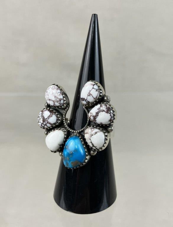 Navajo Style Sterling Silver and Turquoise Ring: Substantial statement ring features a horseshoe design set with turquoise cabochons interspersed with white stones, all secured within a signature rope border setting. The ring is a size 7 1/2 with