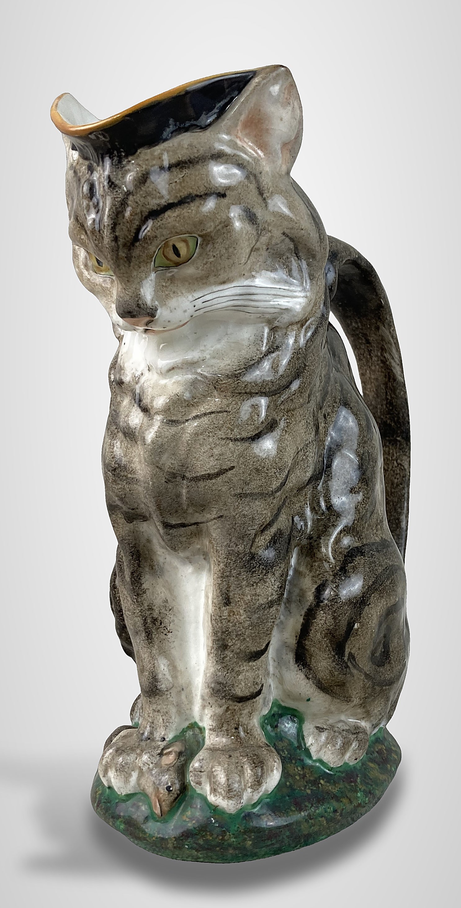 Minton Majolica Figural Cat Pitcher: Rare circa 1870 pitcher was designed by Paul Comolera. It features a striped tabby cat in the act of capturing a mouse beneath its paw, with the handle masterfully formed as the cat's tail. The piece 